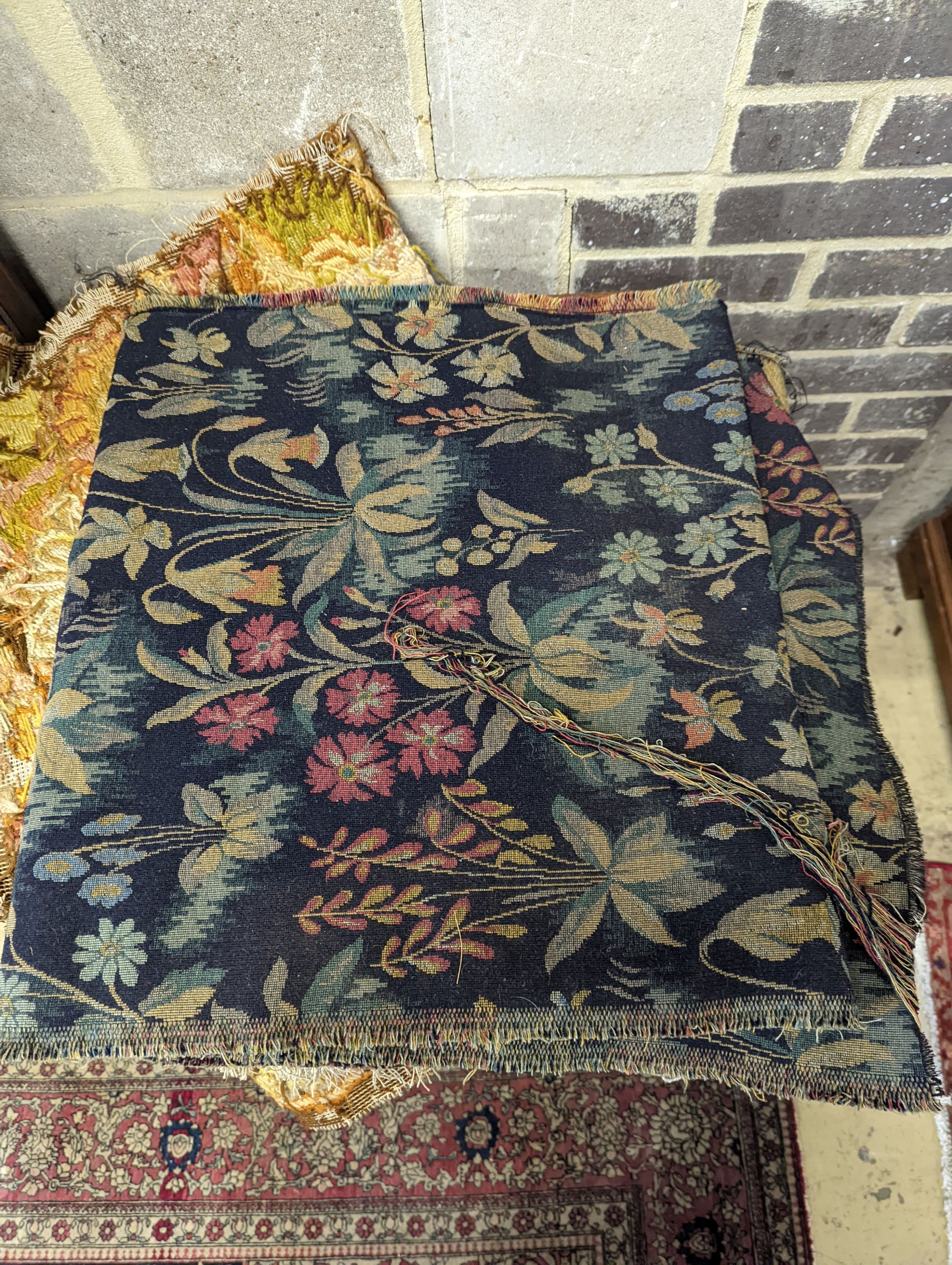 A length of machine tapestry fabric with flowers on a black ground, 420 x 52cm together with a Caucasian rug faced cushion and an antique English needlework panel with stylised scrolls 175 x 67cm